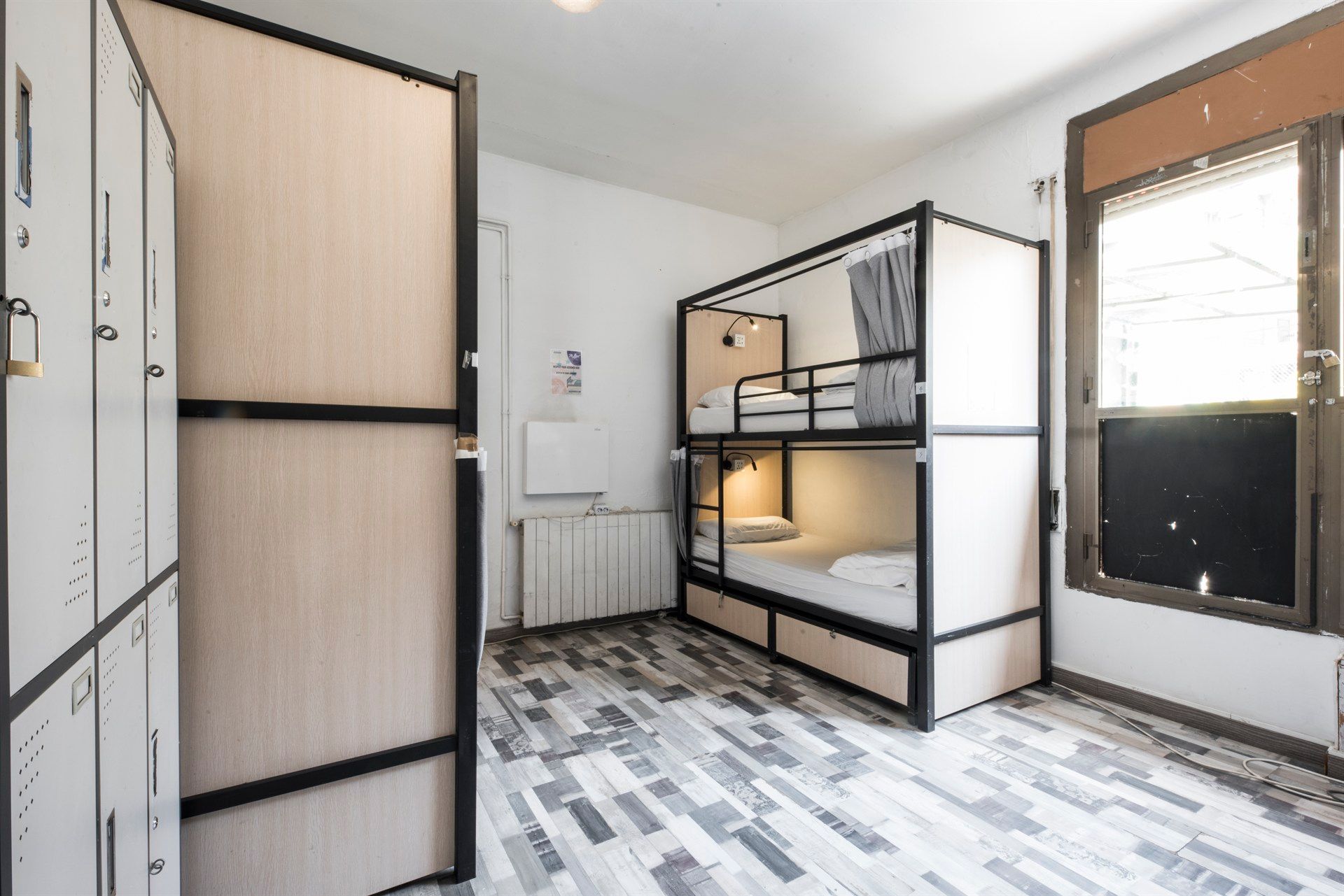 A bunk bed in a room with lockers and a window.
