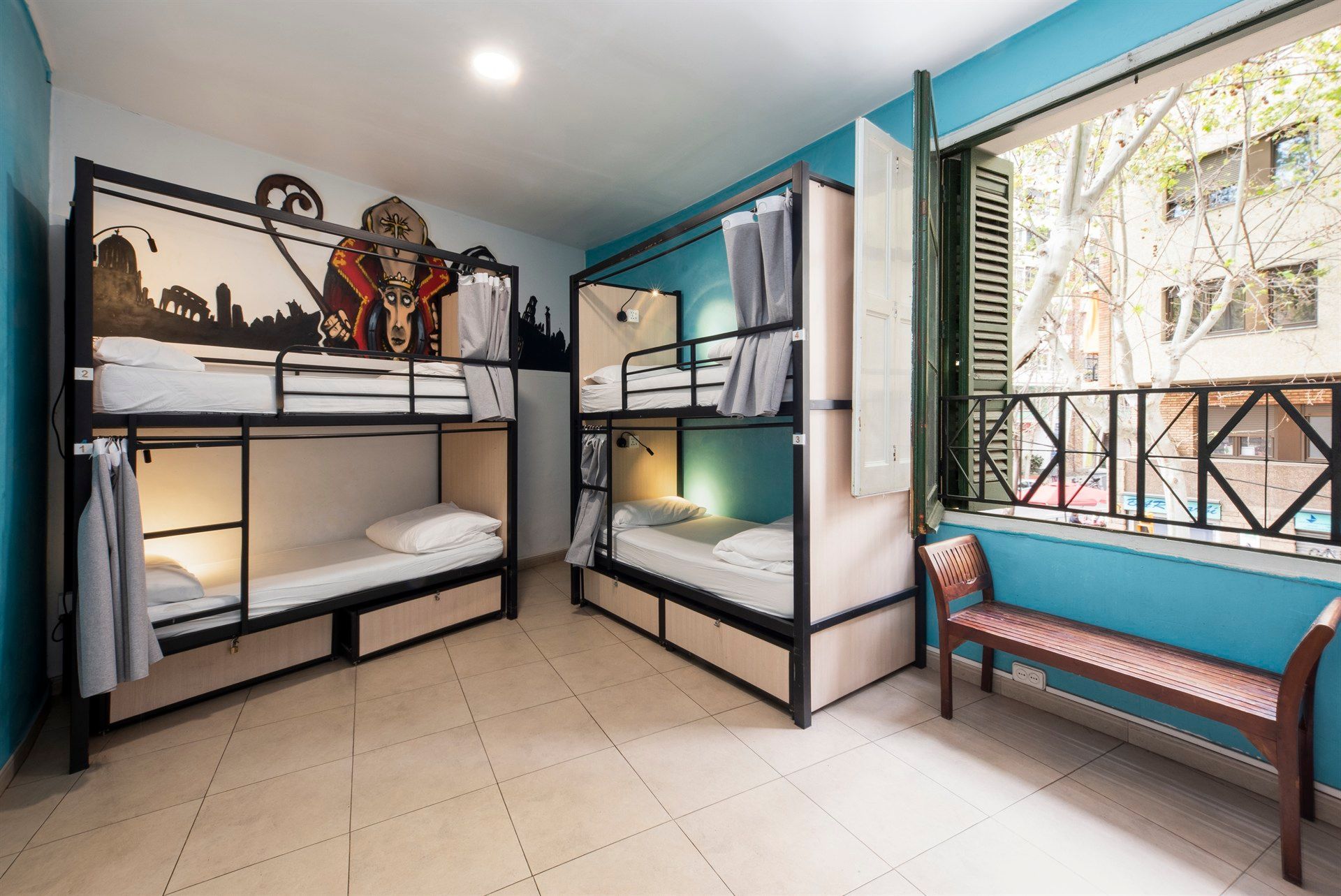 A room with bunk beds , a bench and a window.