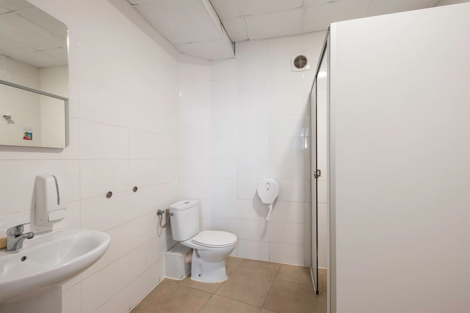A bathroom with a toilet , sink and mirror.