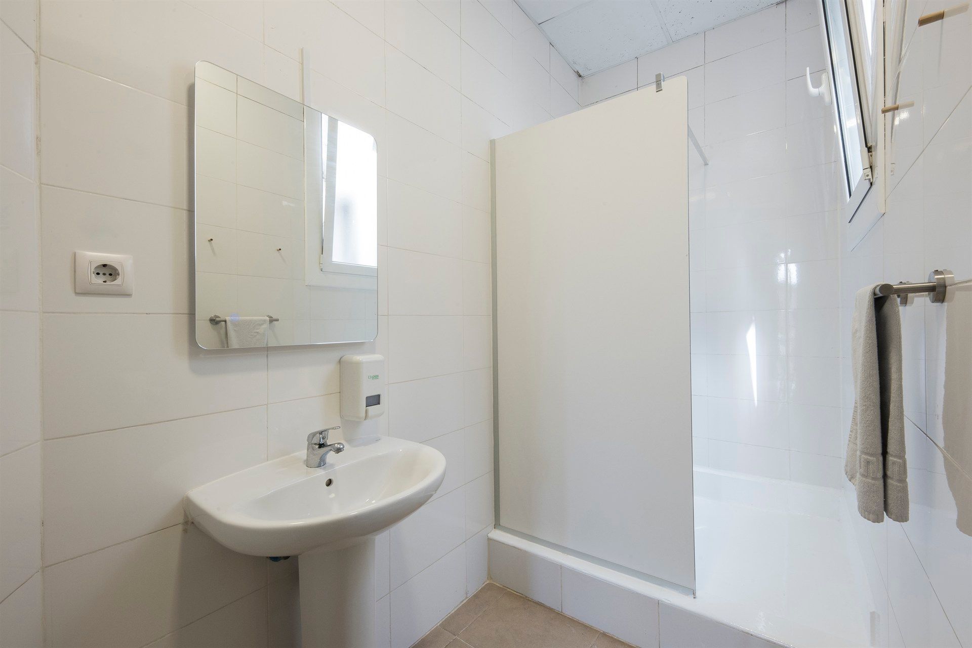 A bathroom with a sink , mirror and shower.