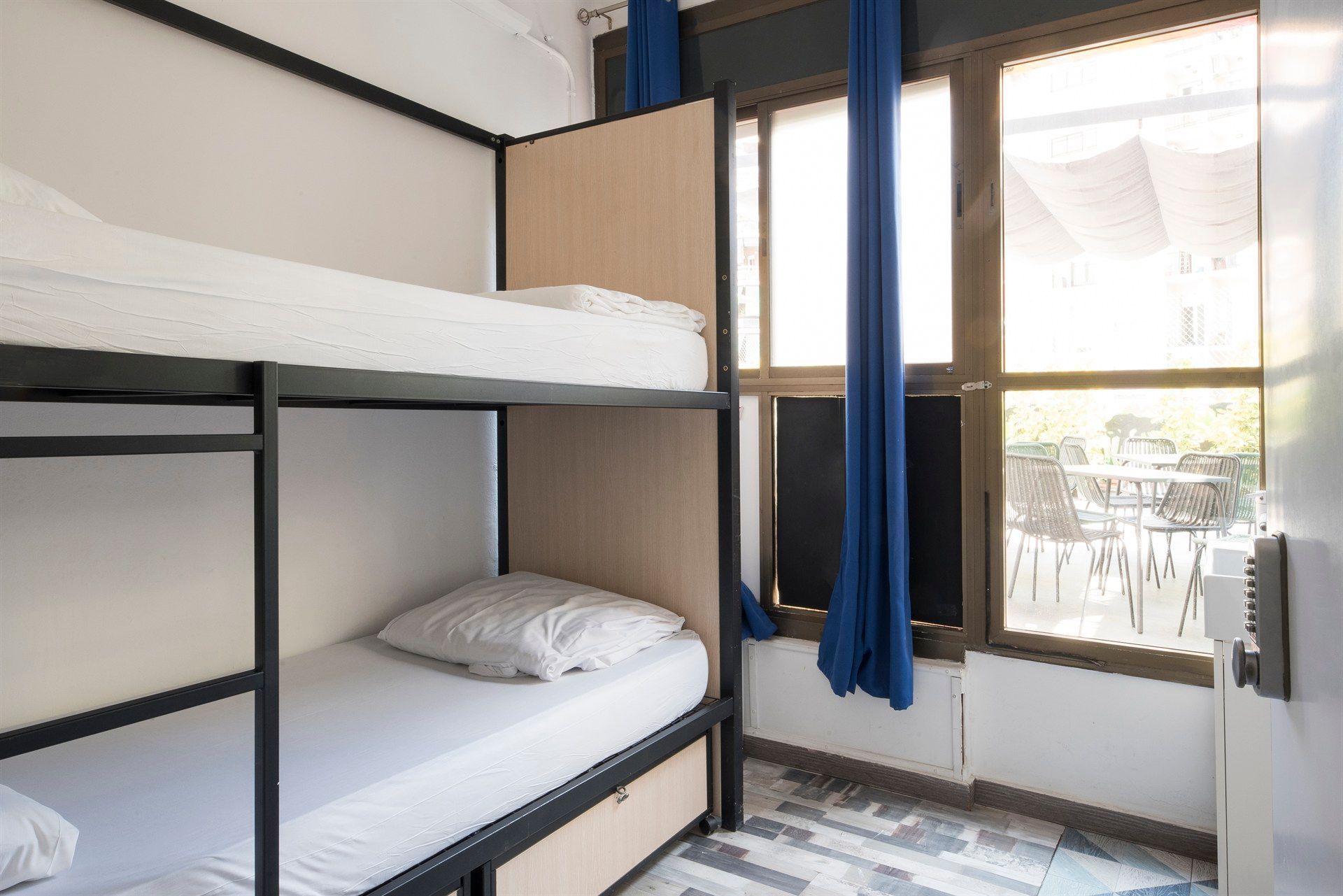 A room with bunk beds and a window with blue curtains
