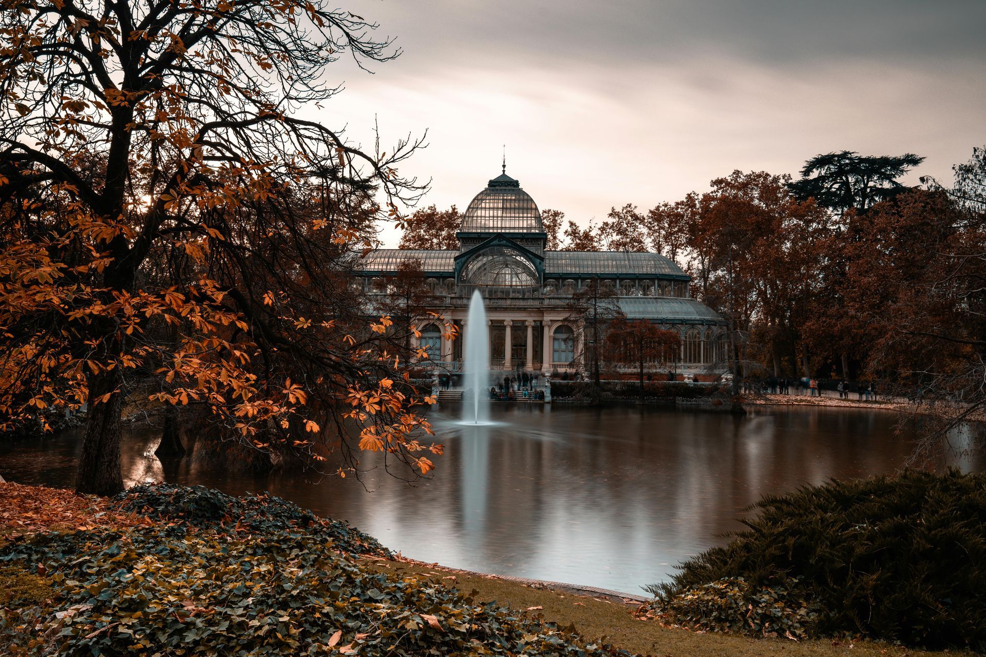 There is a fountain in the middle of the lake in the park.