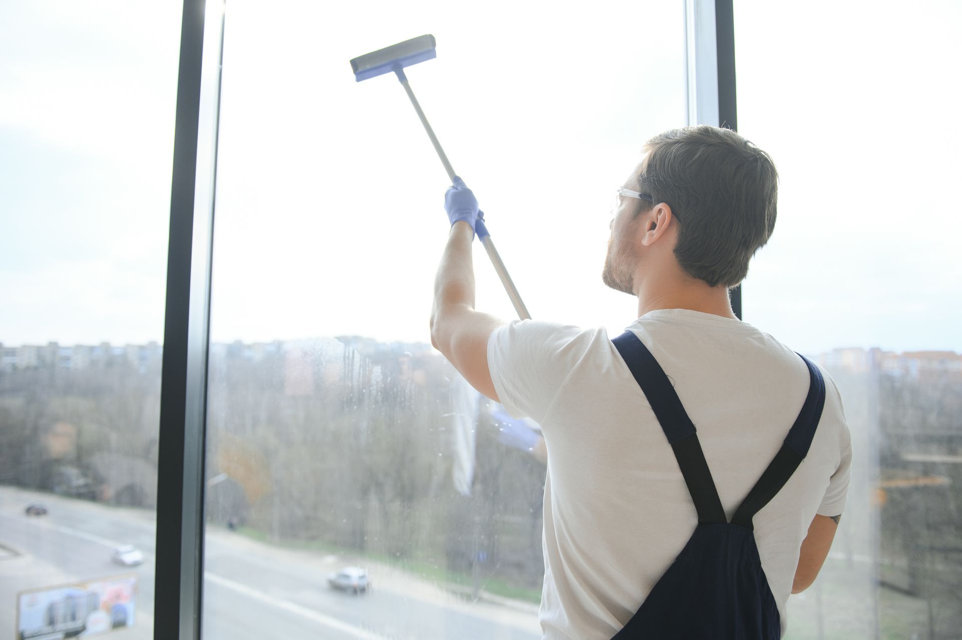 a man is cleaning a window with a mop .