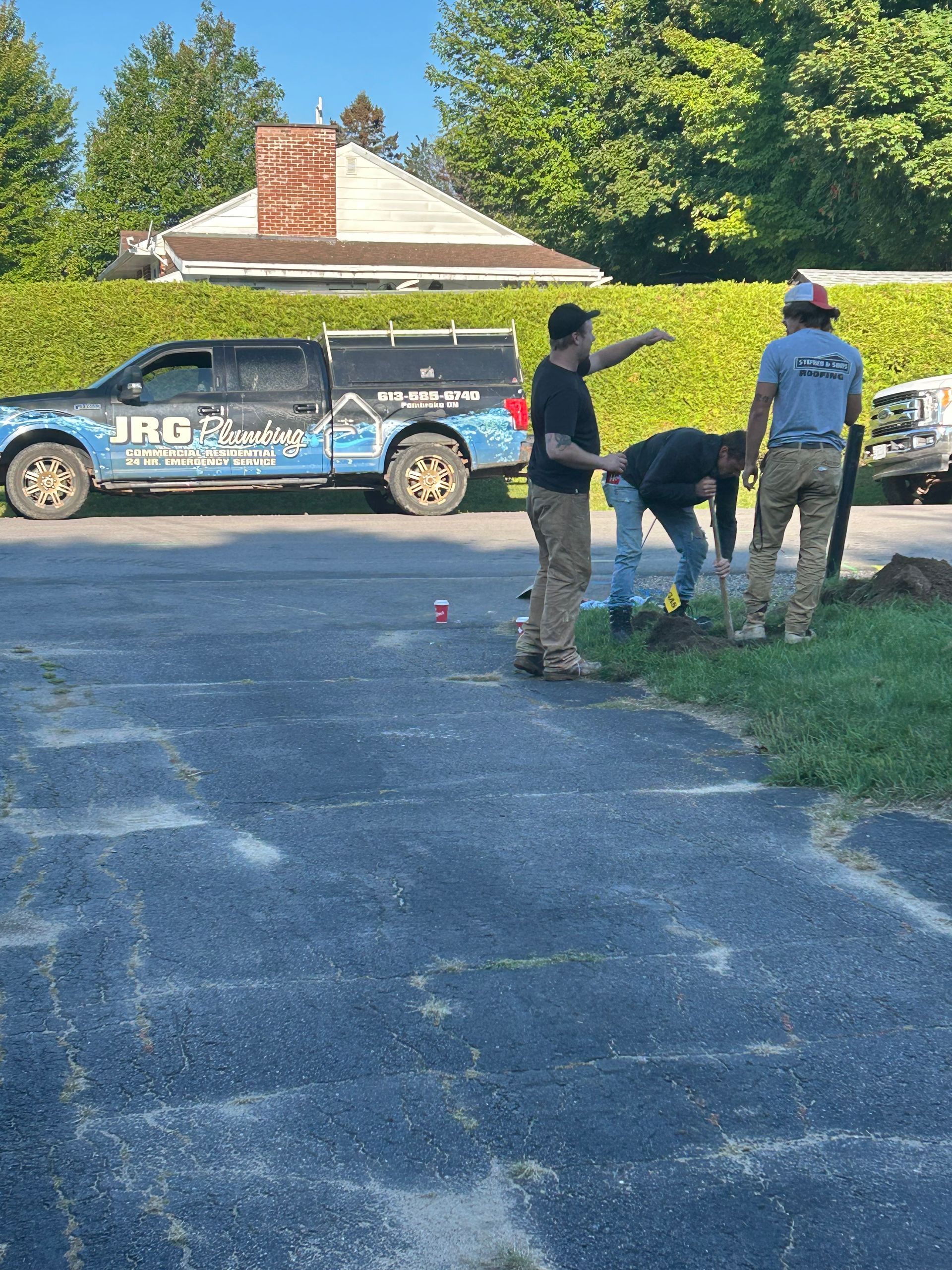 A group of men are working on a driveway next to a truck that says jrg energy