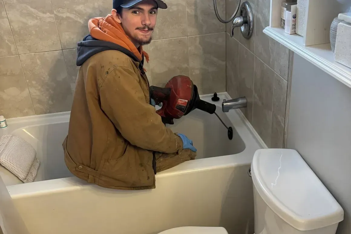 A man is sitting in a bathtub next to a toilet.