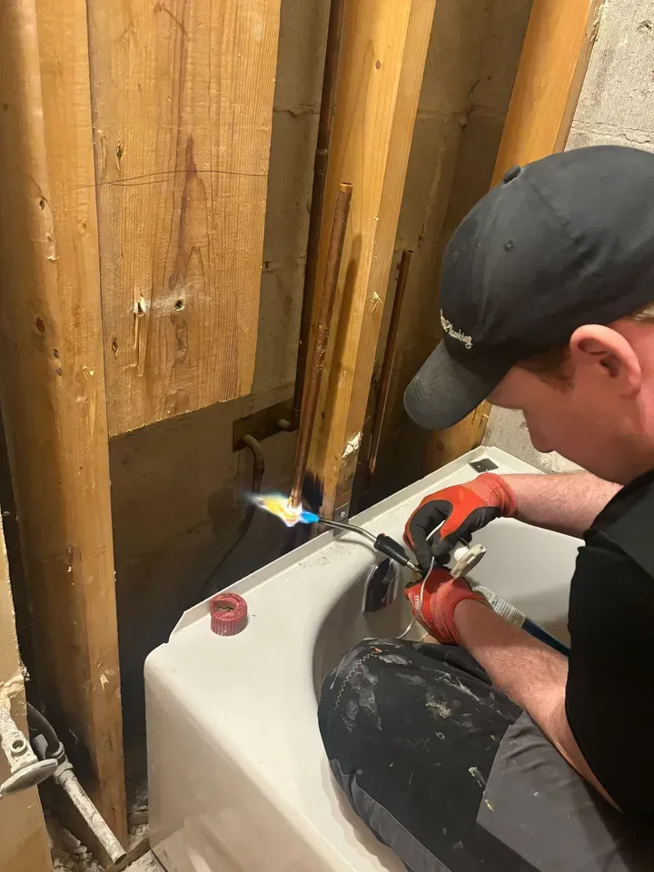 A man is working on a bathtub with a torch.