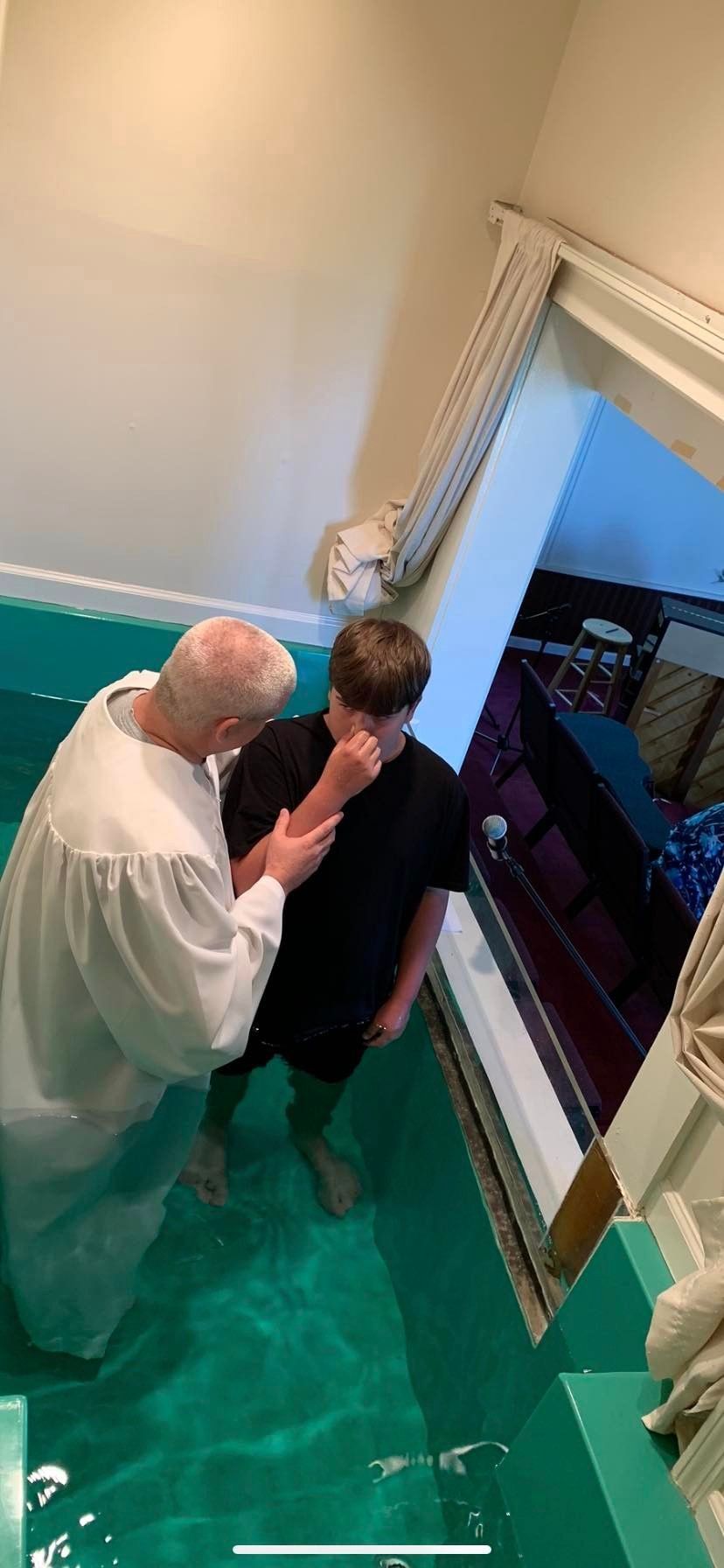 A man is baptizing a young boy in a church.