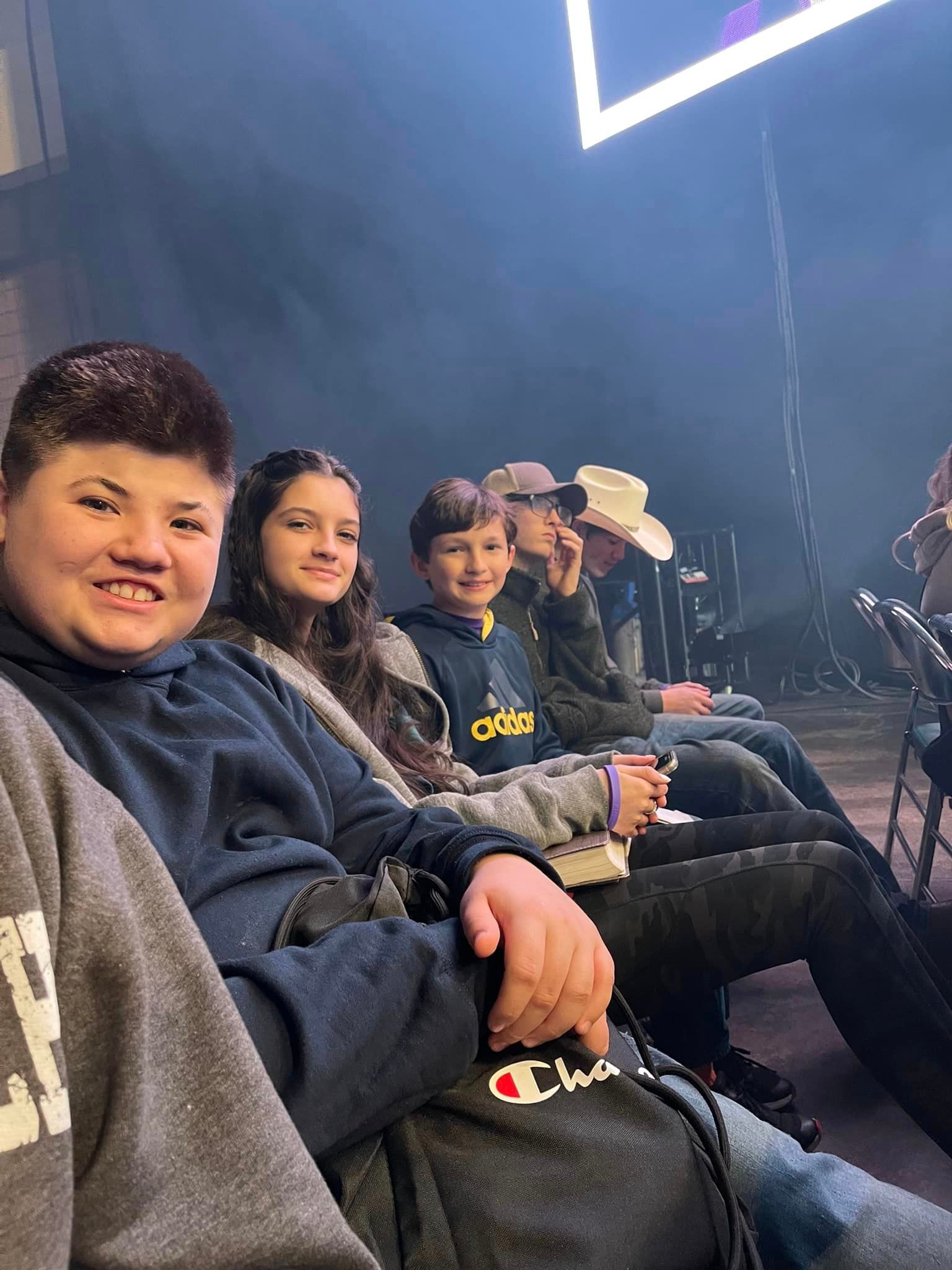 A group of young people are sitting in a row at a conference.