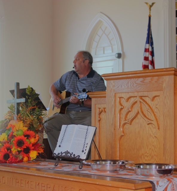 A man sits at a podium playing a guitar