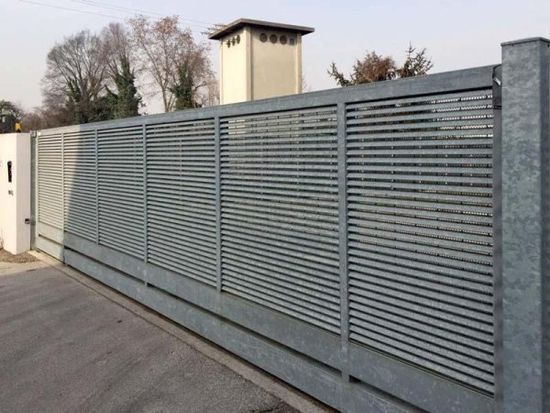 Una recinzione con un cancello scorrevole e un camino sullo sfondo