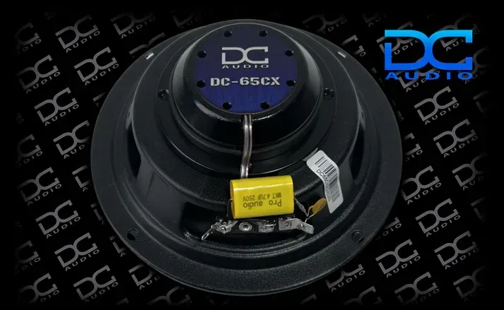 DC Audio 6.5-inch car audio speaker set with black components, blue box, and DC Audio logo on a black background.