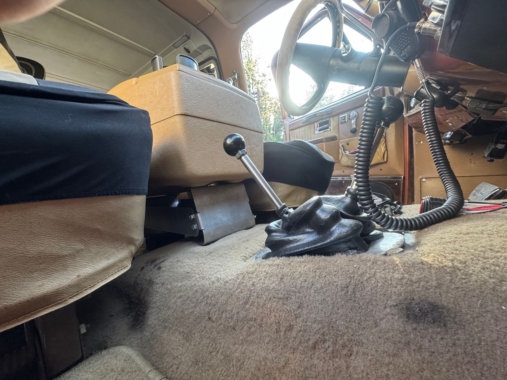 Interior view of a vehicle with a gear shift and a beige carpet.