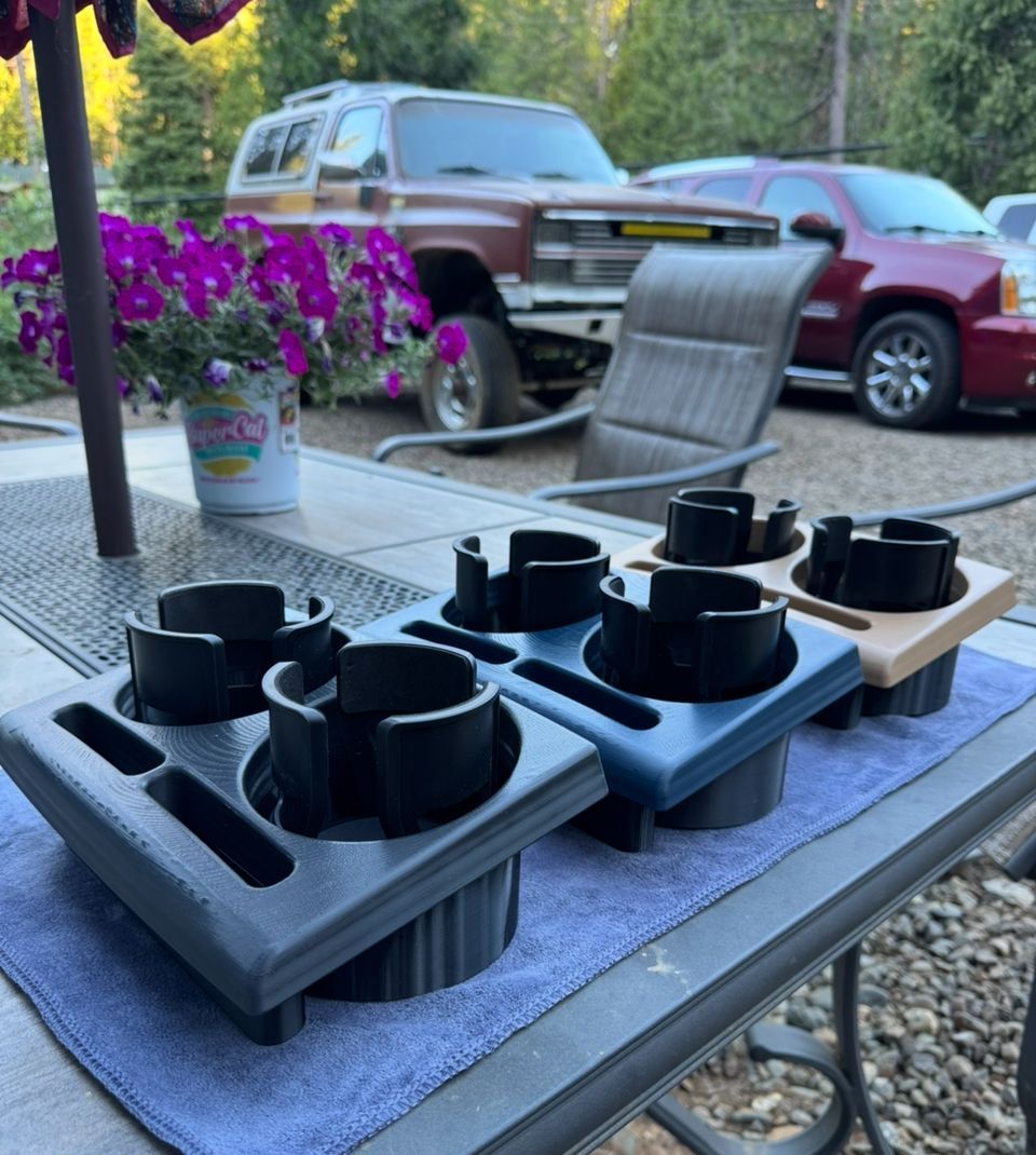 Hand holding a tan console insert next to a tan truck interior with cup holders.