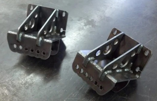 Two welded steel brackets with multiple holes, likely for mounting.