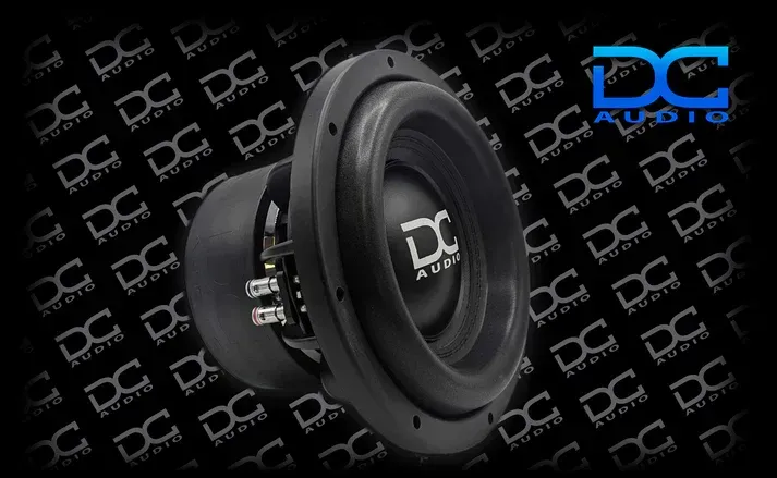 A black subwoofer is sitting on top of a black background.