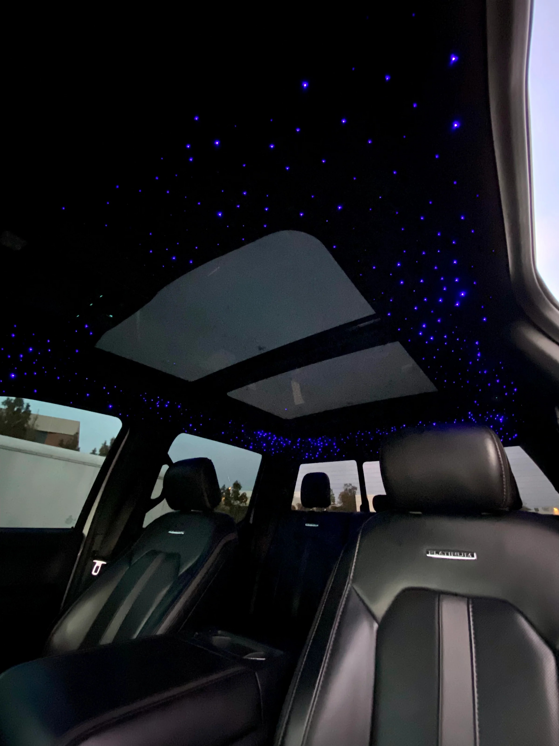 Car interior with a starry night ceiling, blue and red lighting.