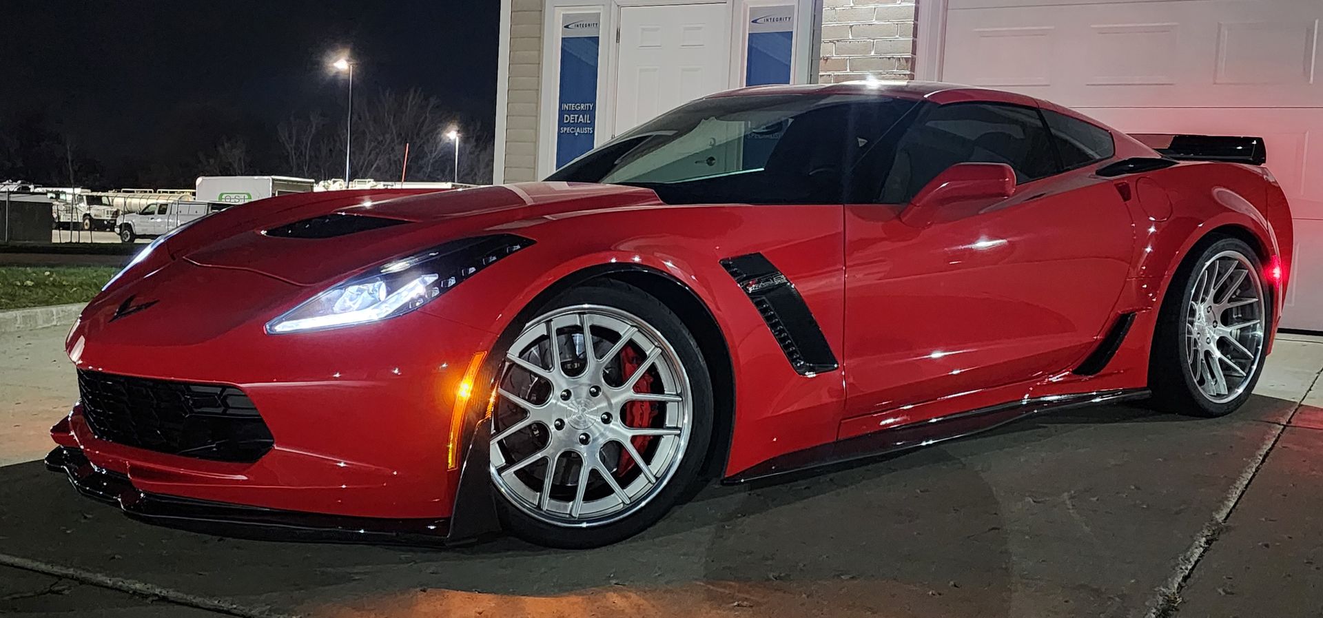 Red Chevrolet Corvette sports car parked outside at night.