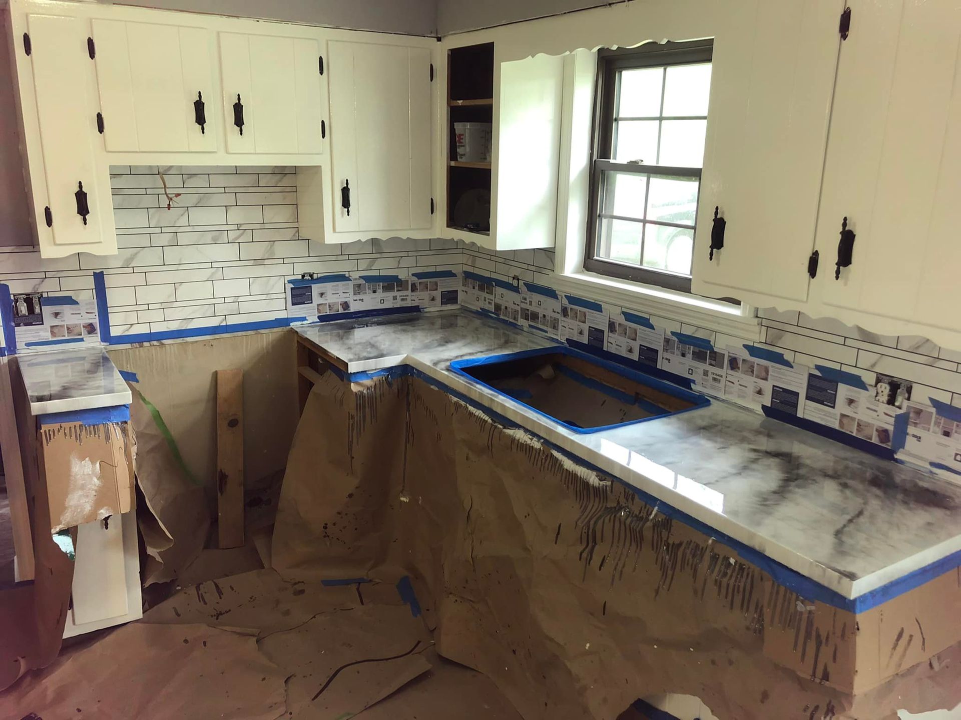 Kitchen undergoing renovation, with cabinets, new countertops, and tiling in progress.