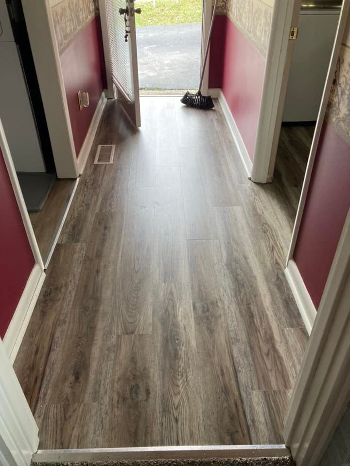 Hallway with wood-look flooring, burgundy walls, and an open glass door to the outside.