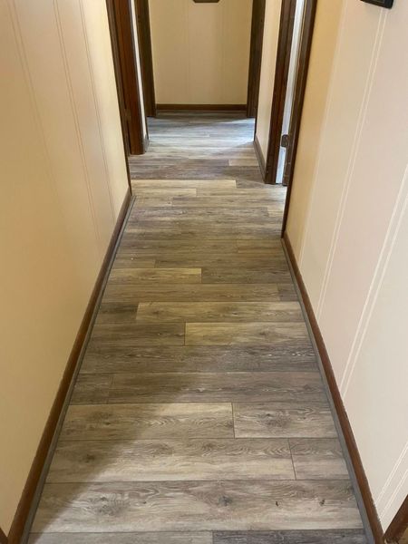 Narrow hallway with wood-look flooring, beige walls, and wood door frames.