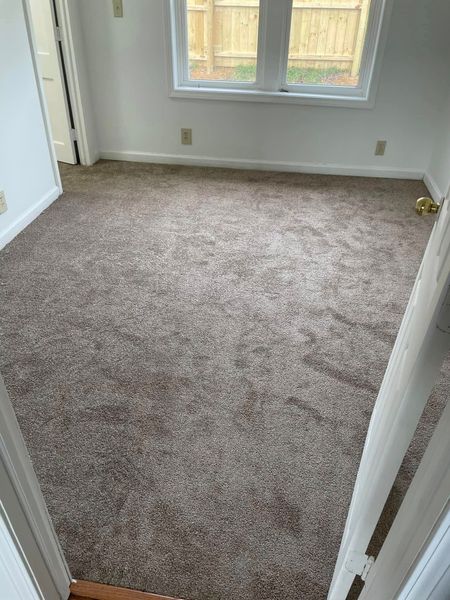 Brown carpeted room with a window and a doorway.