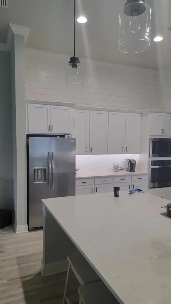 Modern kitchen with white cabinets, stainless steel fridge, and large island.