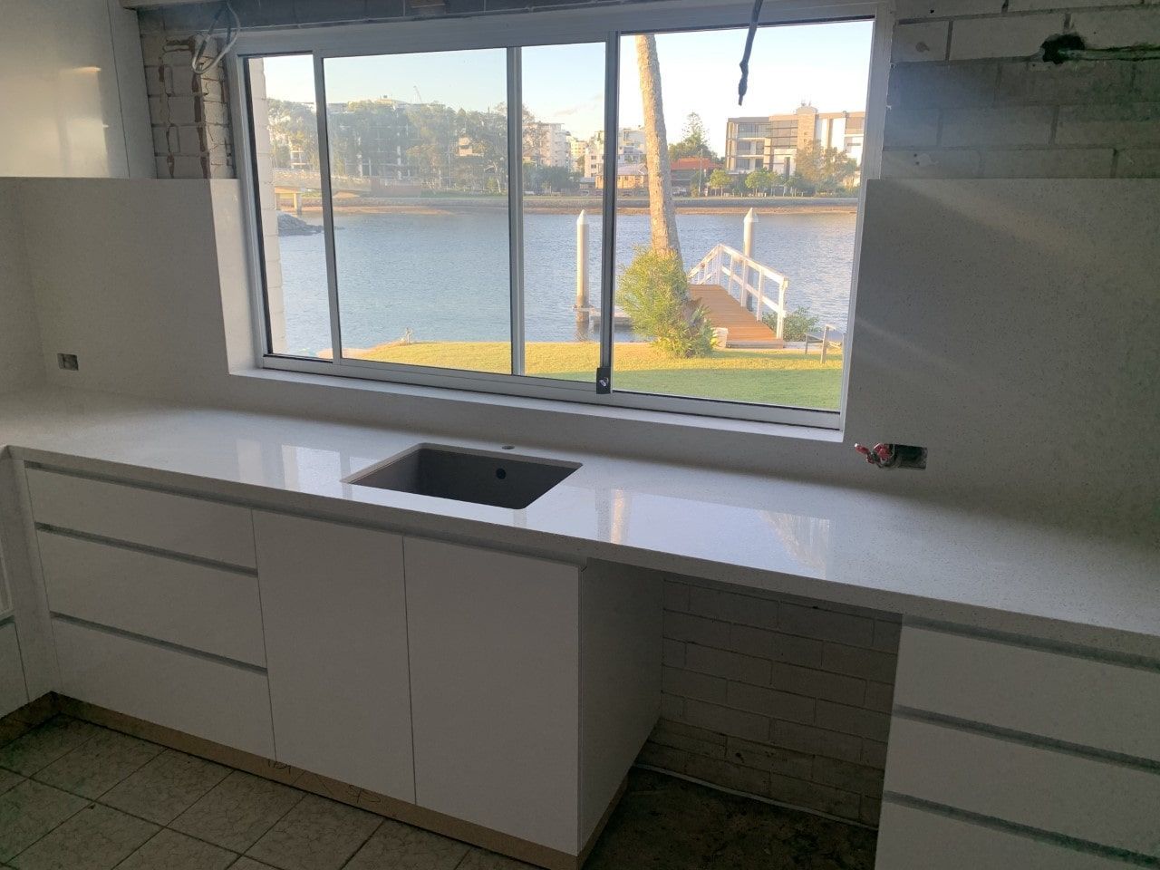 A Kitchen With A Sink And A Window Overlooking A Body Of Water — Southeast Stone Pty Ltd In Caloundra West, QLD