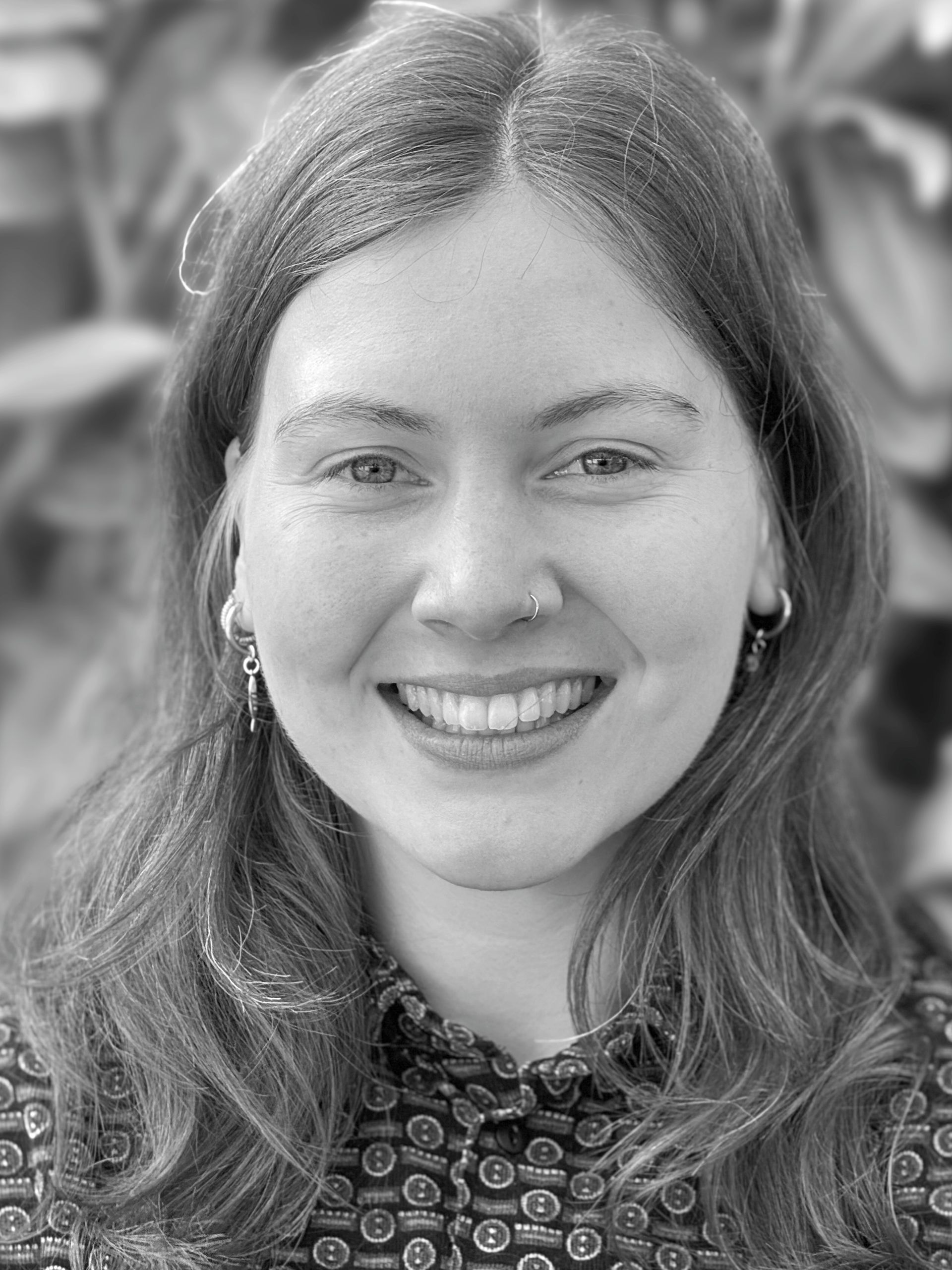 A woman in a black shirt is smiling in a black and white photo.