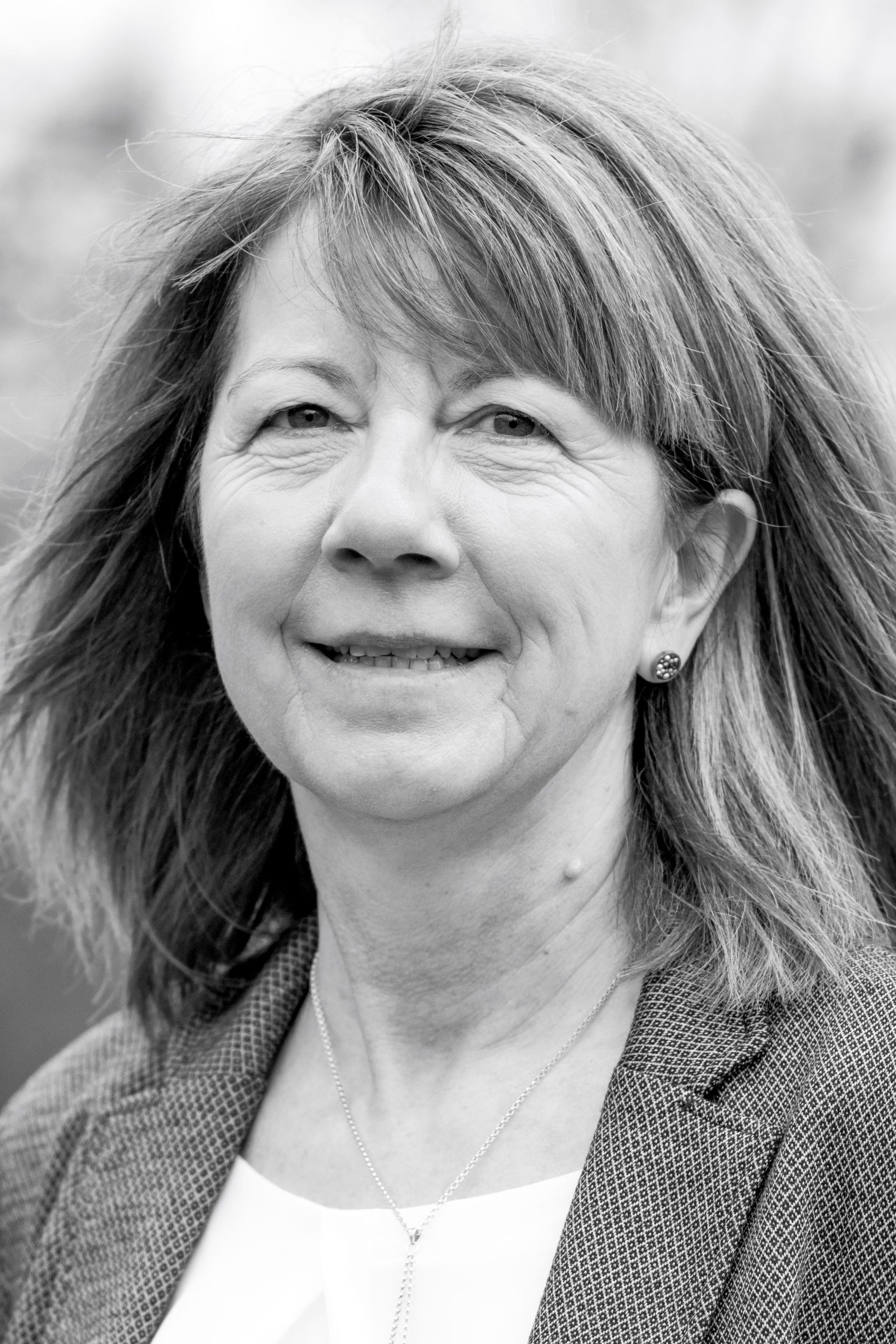 A woman with long hair is smiling in a black and white photo.