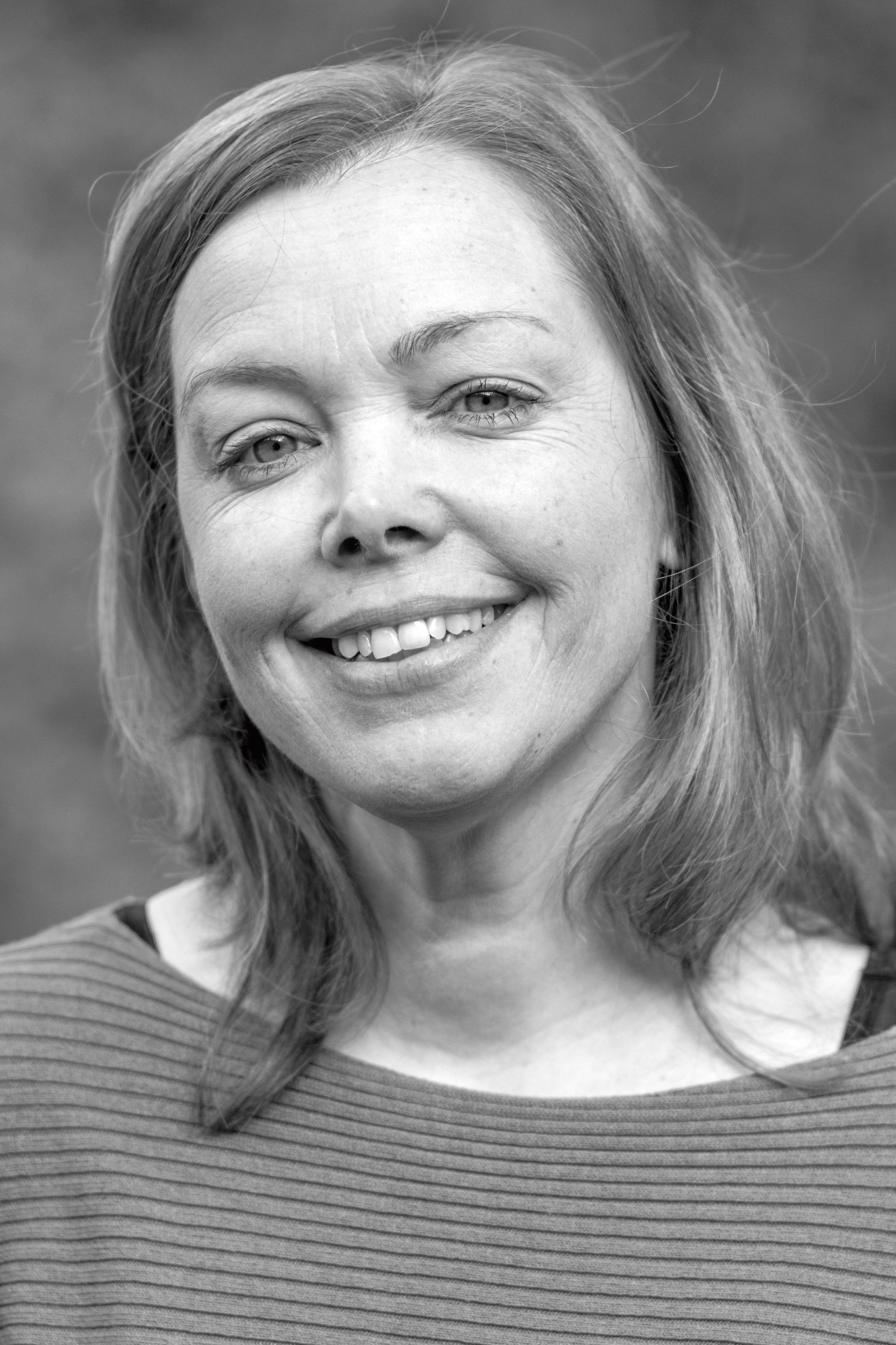A woman is smiling in a black and white photo.