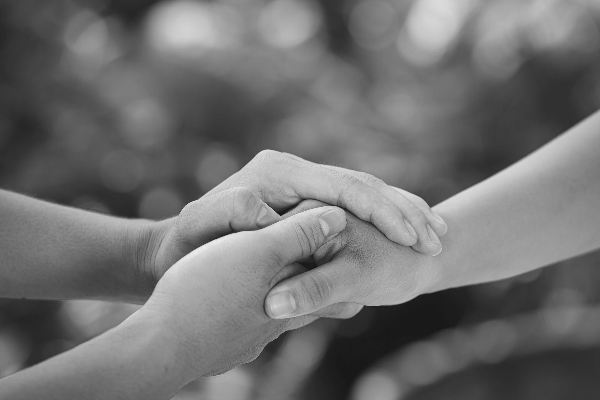 Two people are holding hands in a black and white photo.