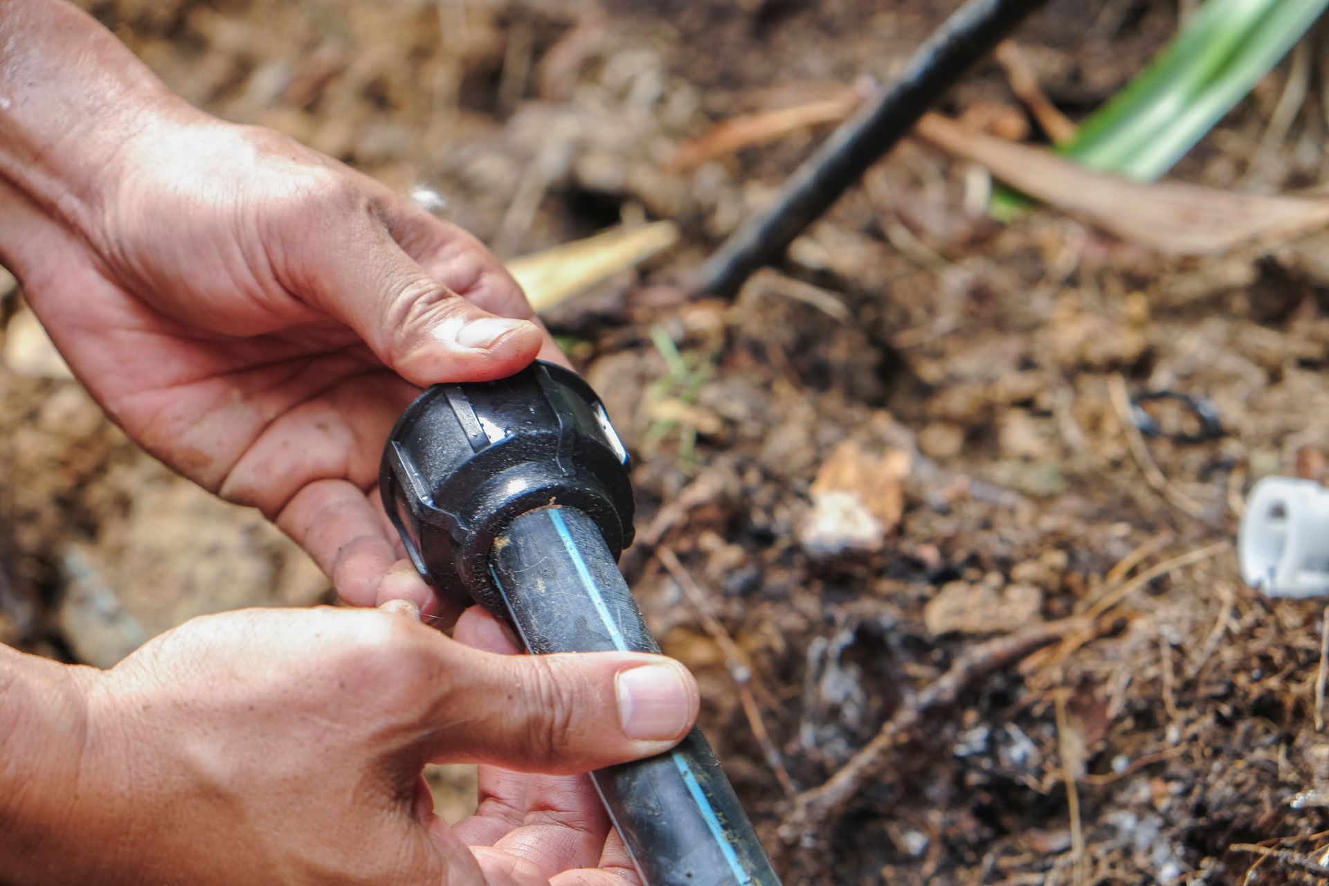 A person is holding a black pipe in their hands.