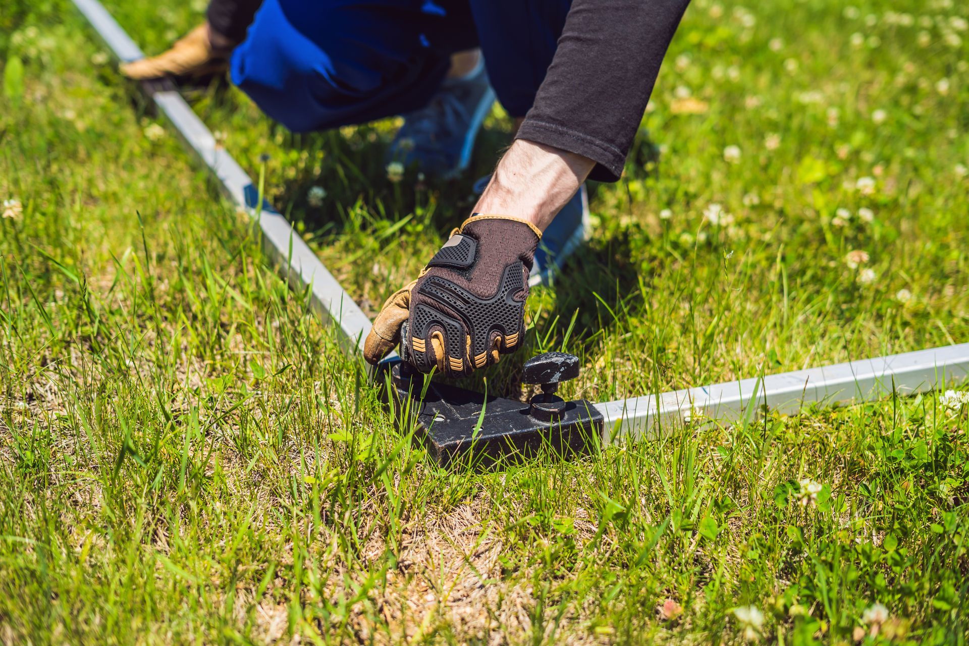 A person is kneeling down in the grass holding a piece of metal.