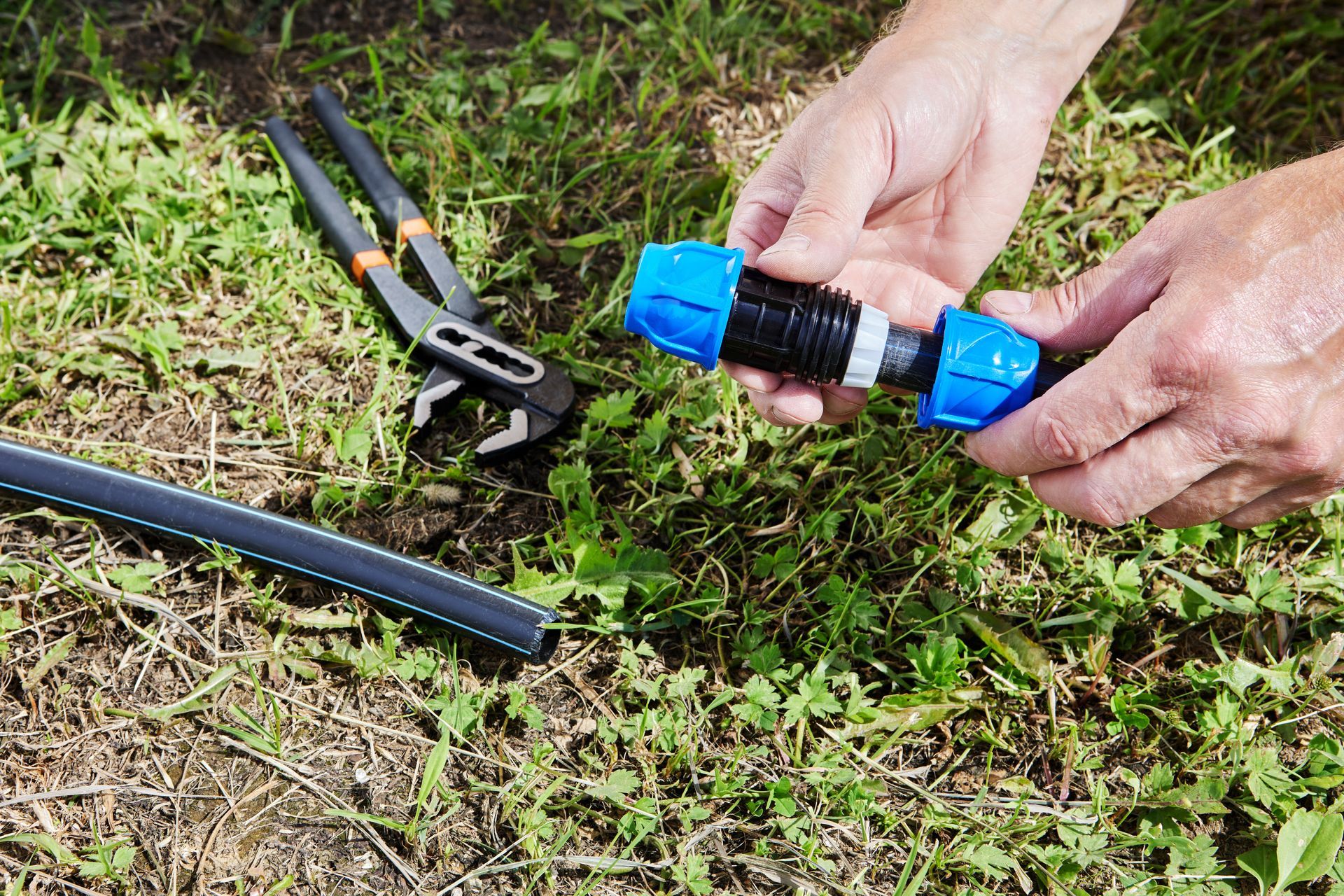 A person is holding a blue hose connector in their hands.