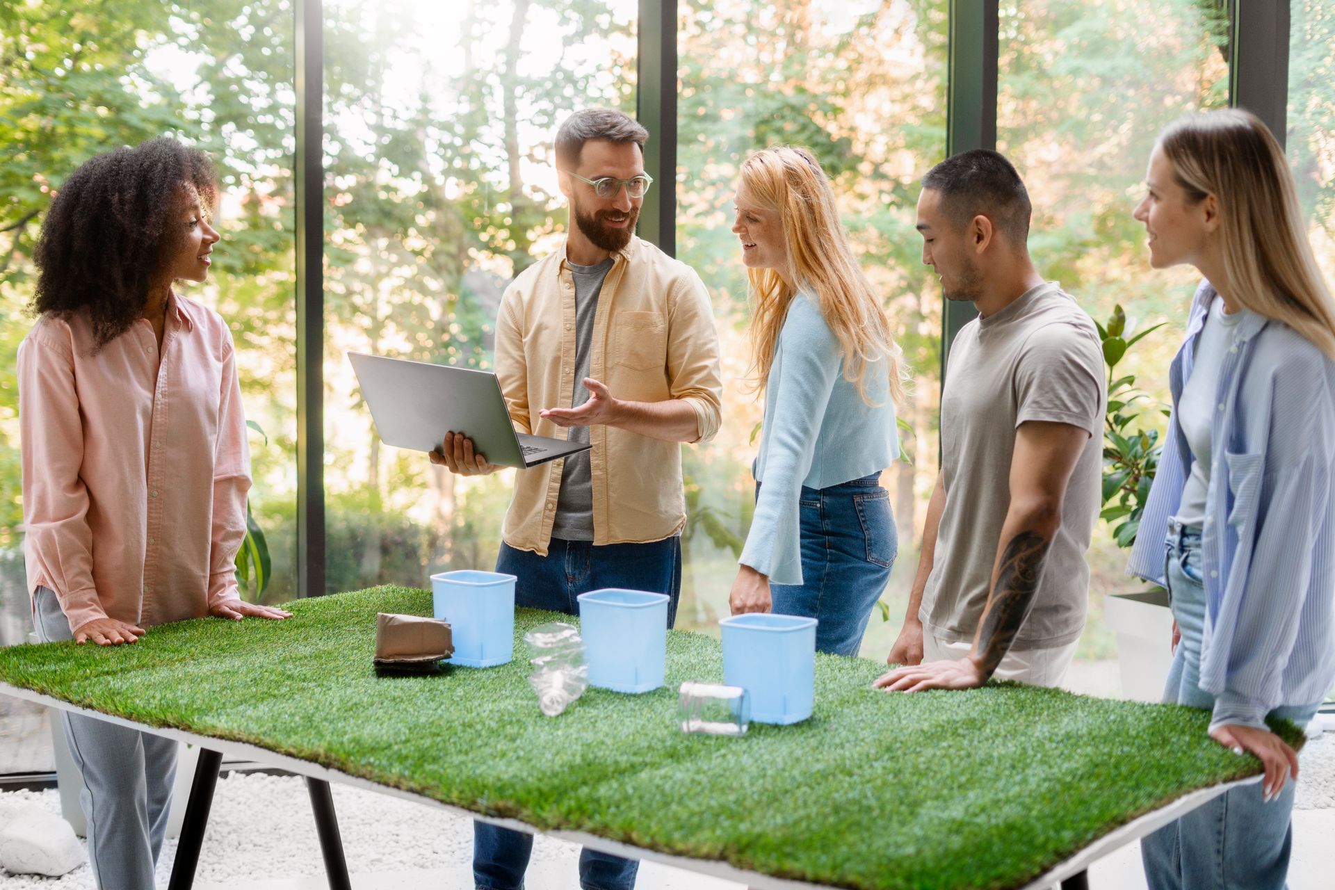 A group of people are standing around a table made of artificial grass.