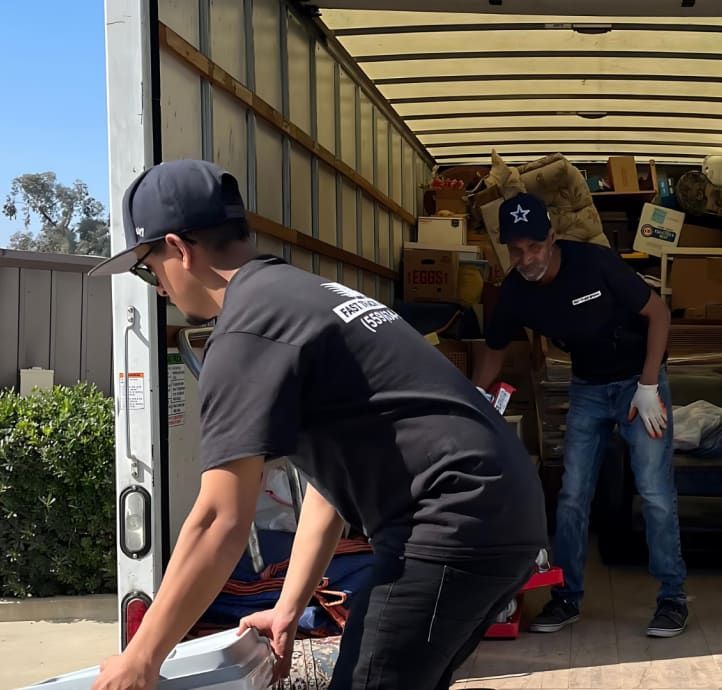 Two workers loading boxes into a moving truck on a sunny day
