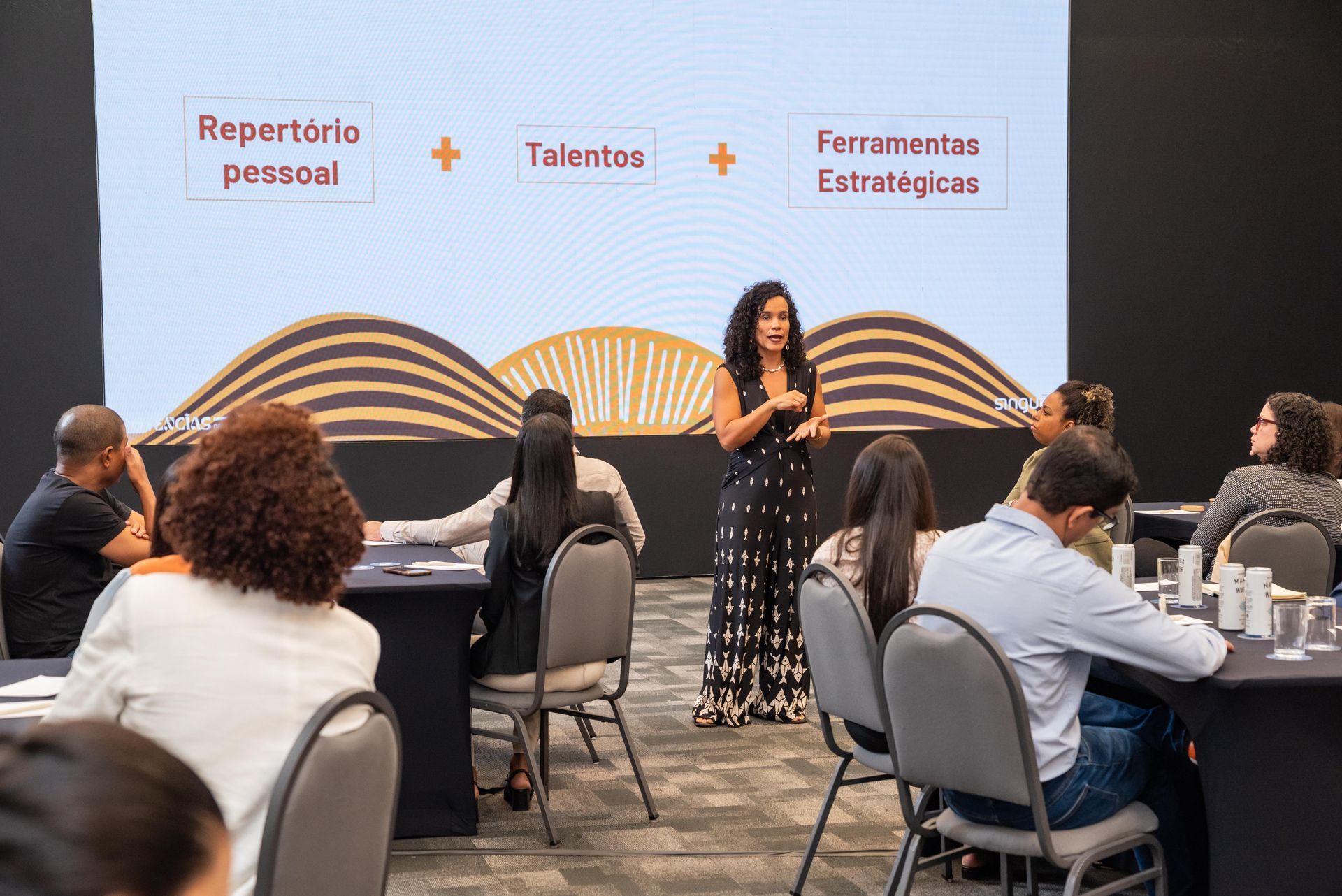 Woman presenting to a group in a conference setting.
