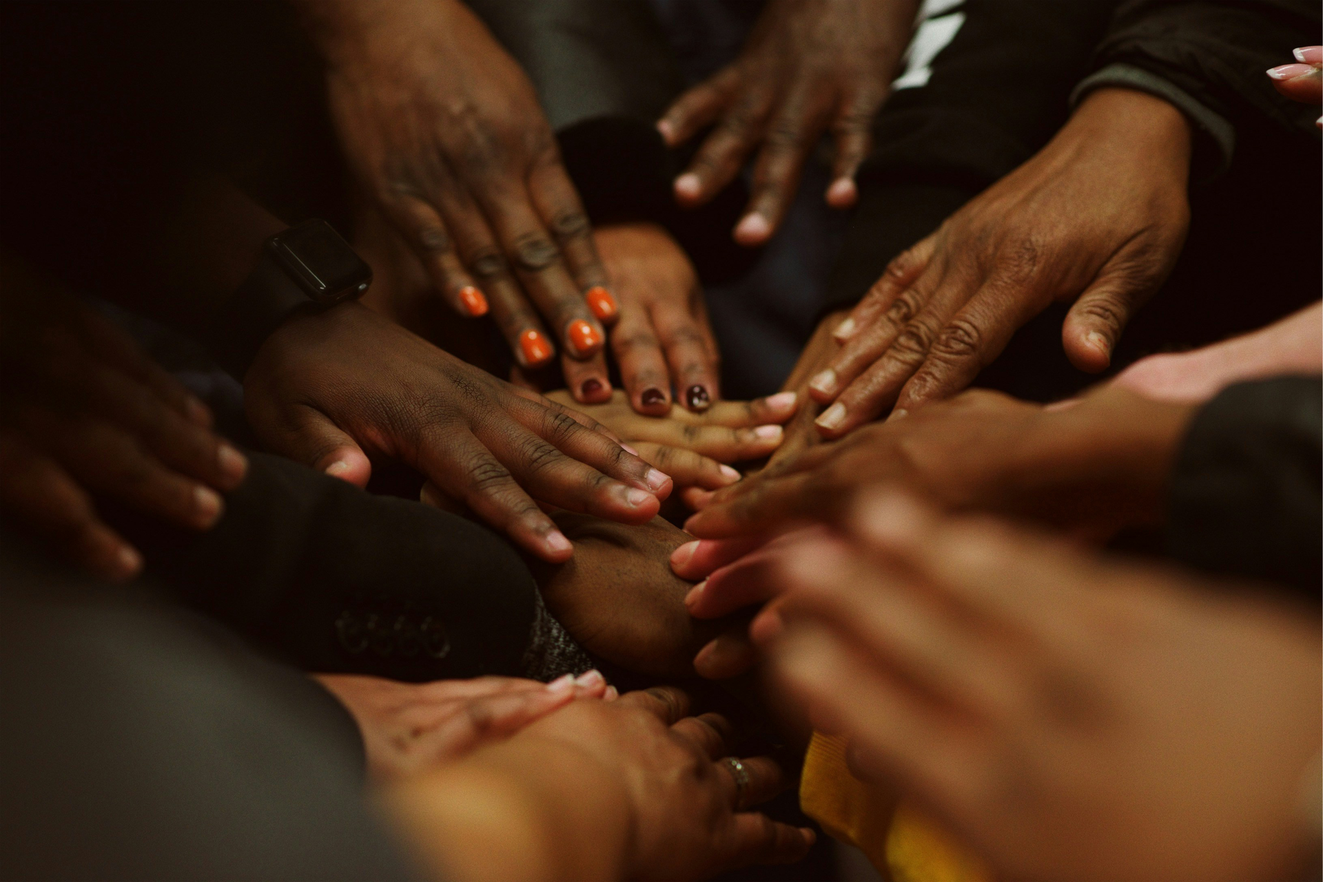 Mãos de pessoas diversas unidas em círculo, demonstrando unidade.