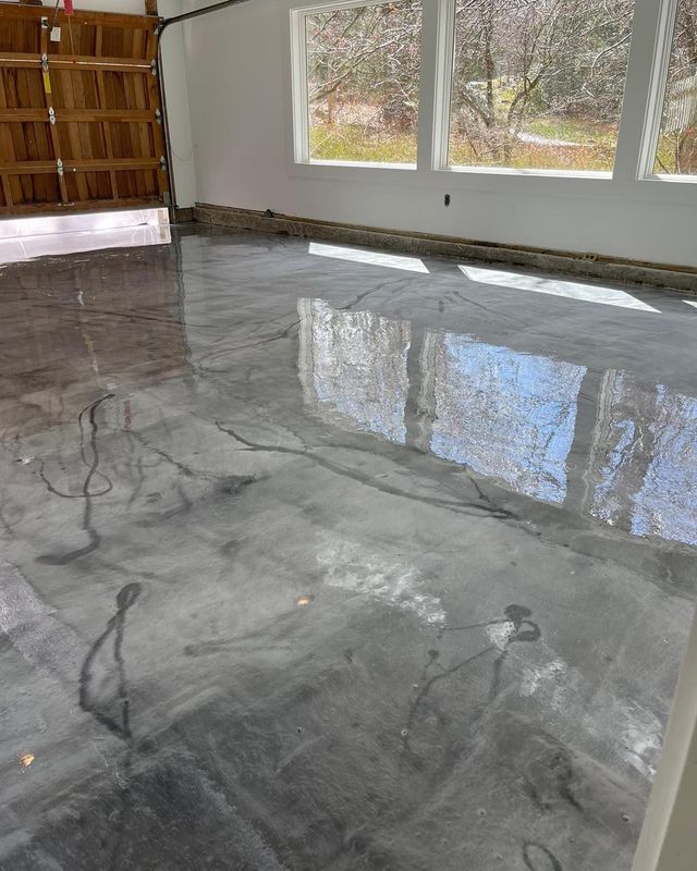 Polished gray concrete floor reflects light in a bright room with windows. Garage door visible.