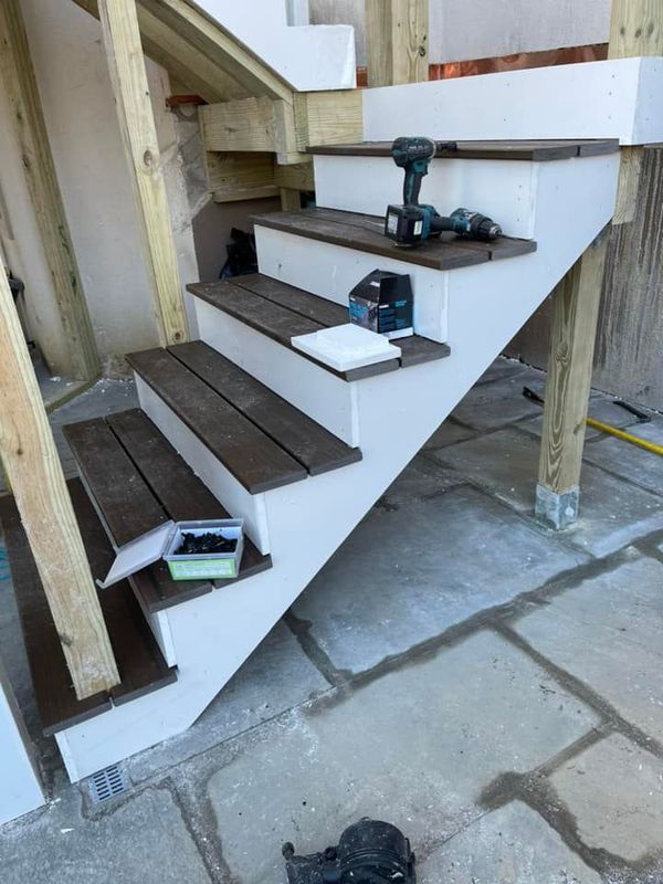 Exterior stairs with white risers, brown treads, and tools on them.