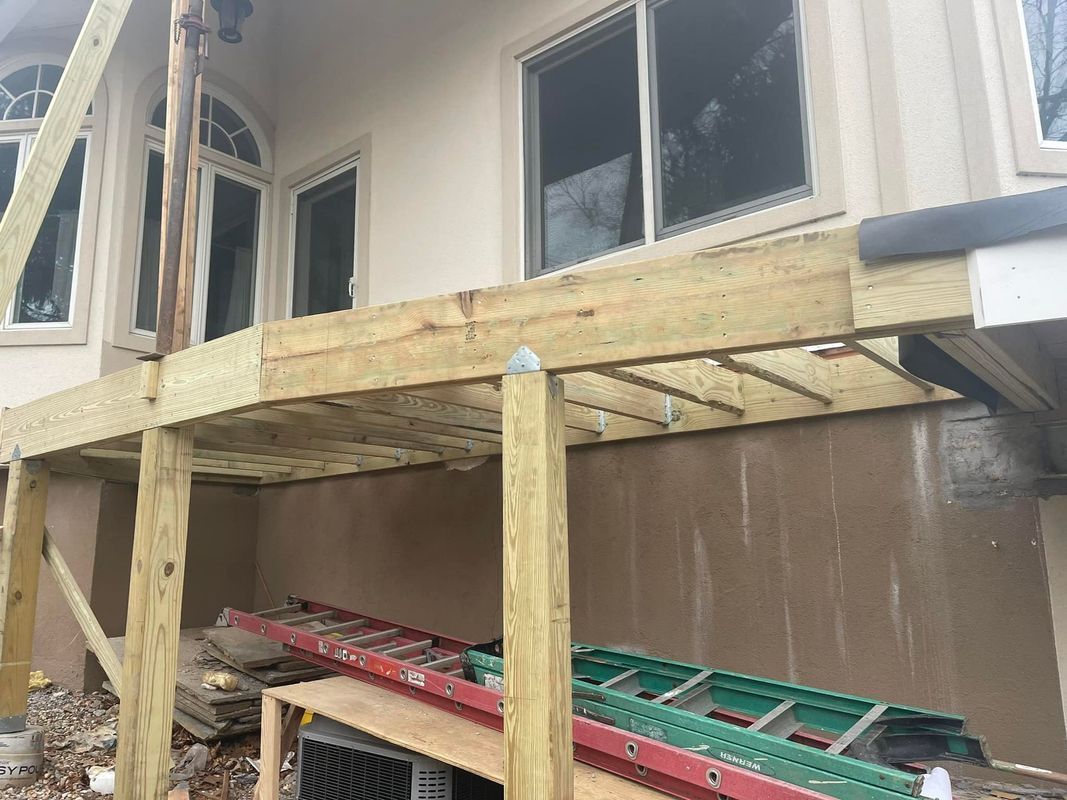 Newly constructed wooden deck attached to a house with ladders propped against it.