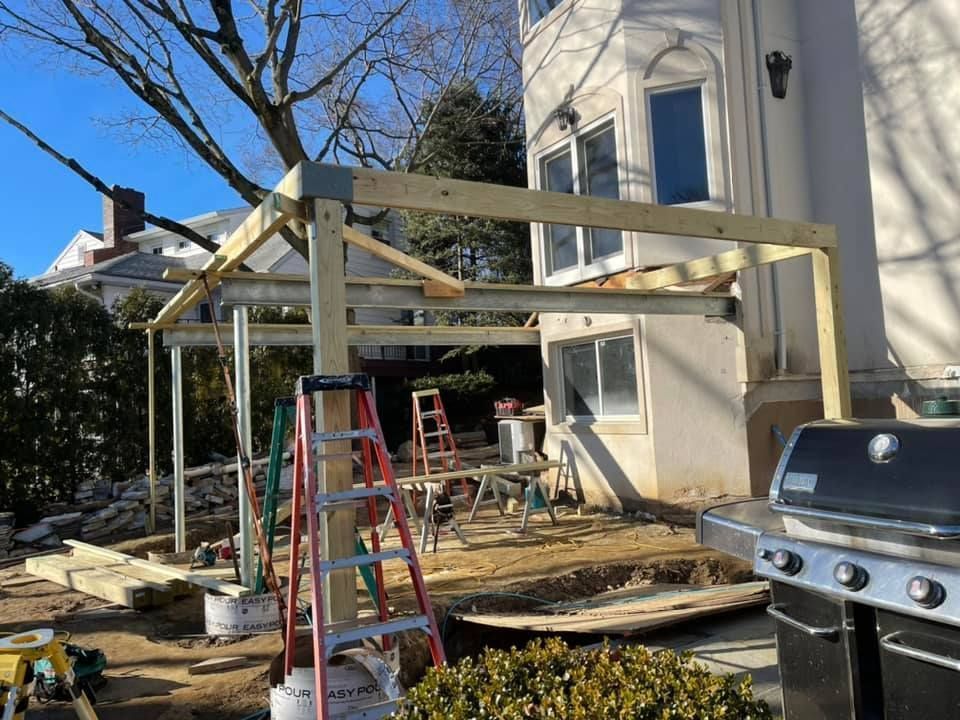 Construction of a wooden pergola attached to a house; daylight setting with tools and grill.