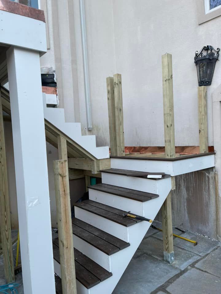 Outdoor stairway construction with white risers and brown treads; wood posts, and a landing.