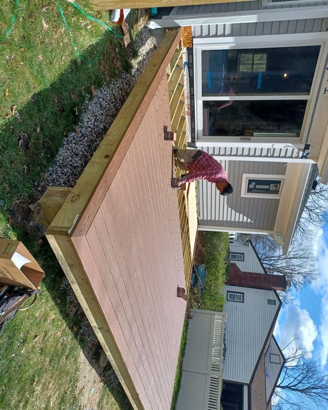 A person builds a deck with brown decking. Sunny outdoor setting.