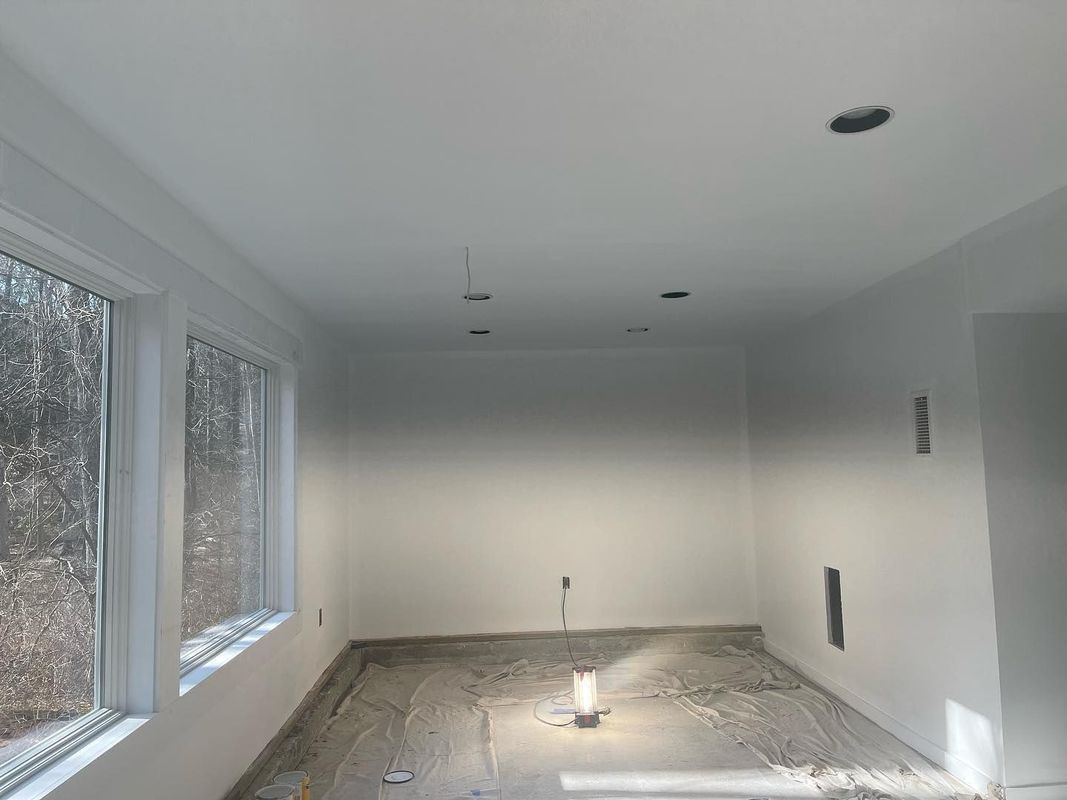Empty room with white walls, ceiling, trim, and windows; unfinished concrete floor; recessed lighting holes.