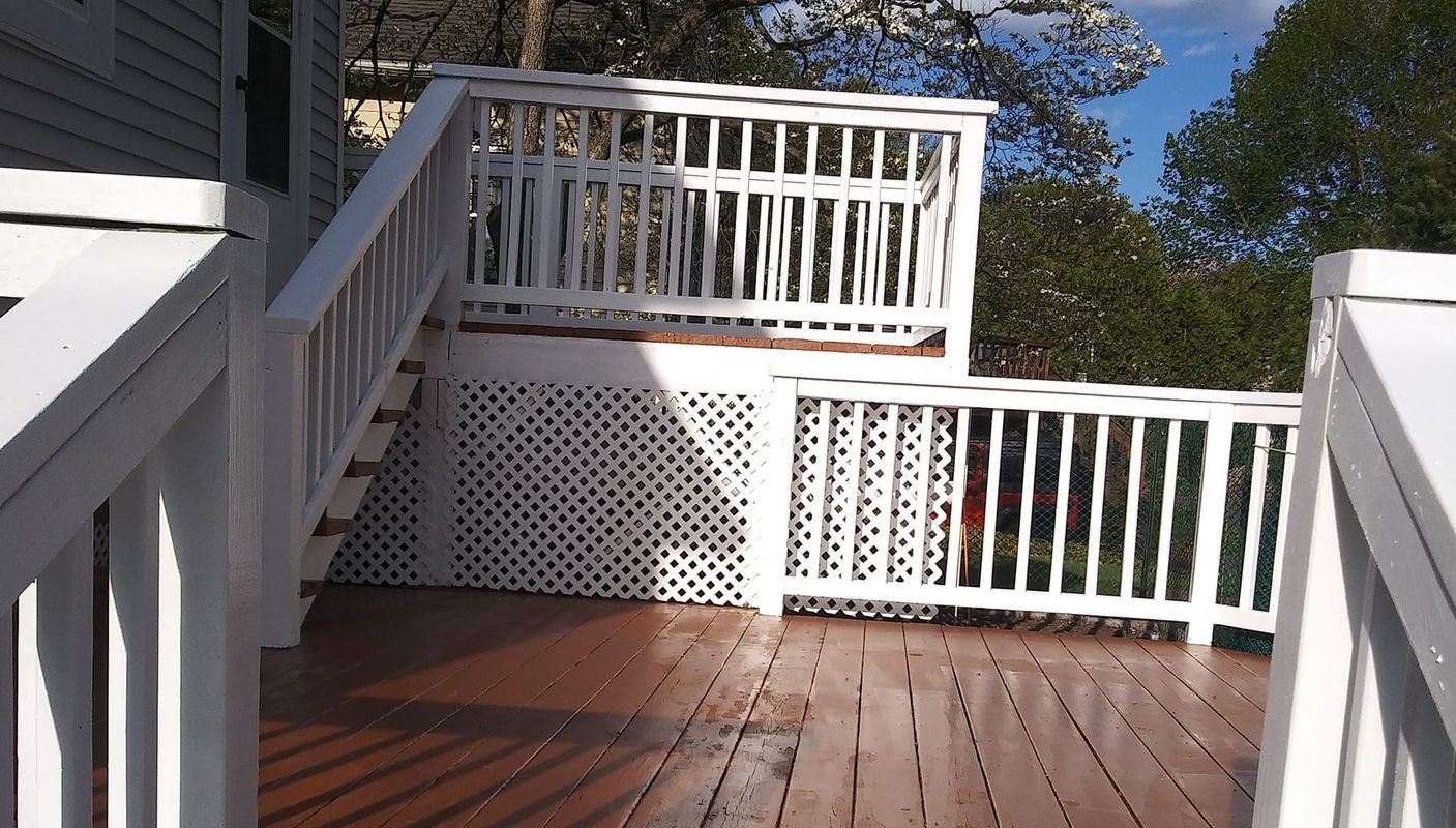 White wooden deck with stairs and railings. Lattice detail under the upper deck.