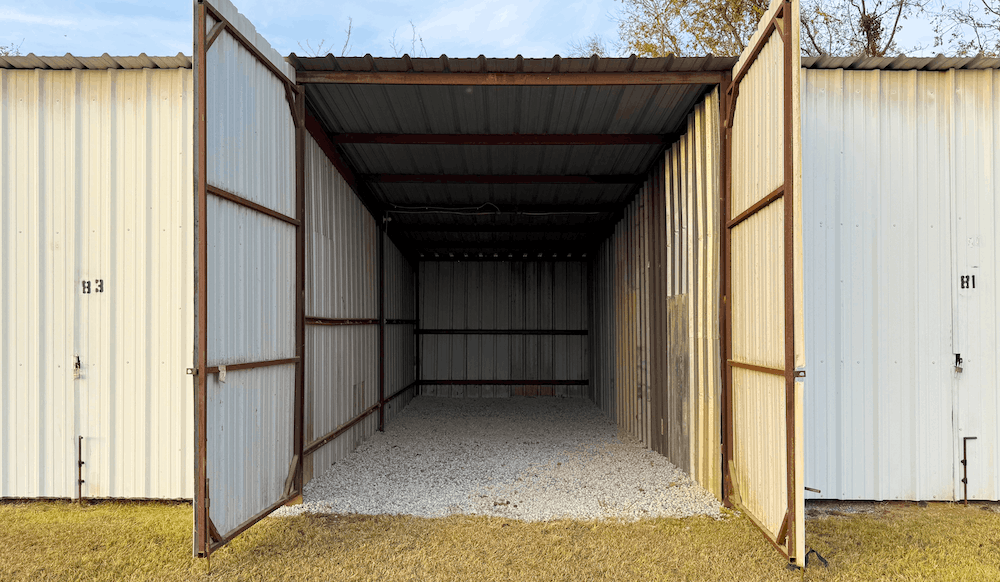 Open storage unit with gravel floor and metal walls.