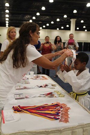 Volunteer giving award to little boy in judo uniform