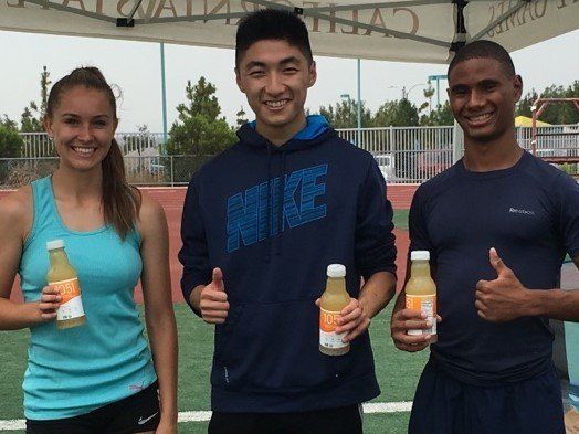 female and two male athletes holding a sports drink in their hands with their thumbs up