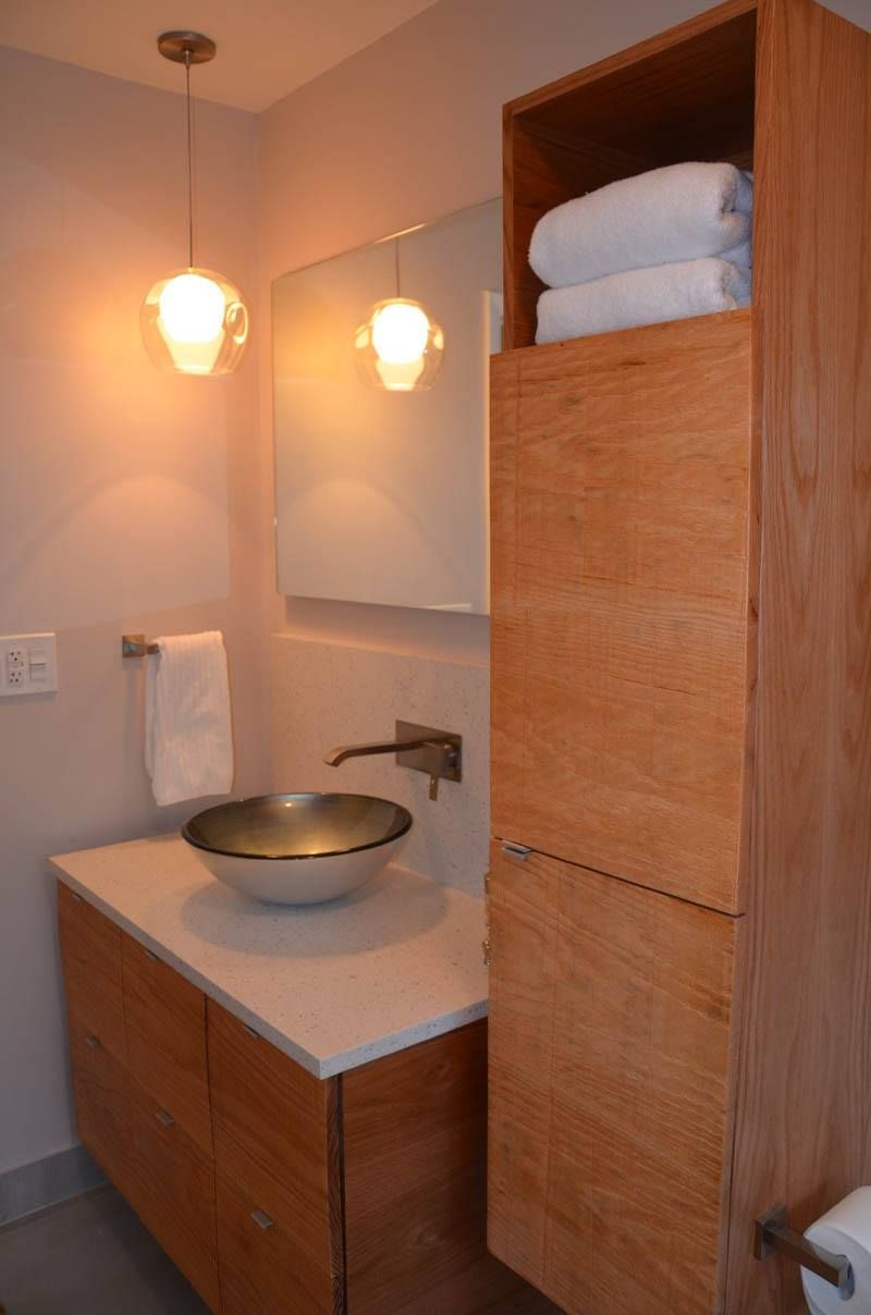 A bathroom with a sink , mirror , towels and a wooden cabinet.